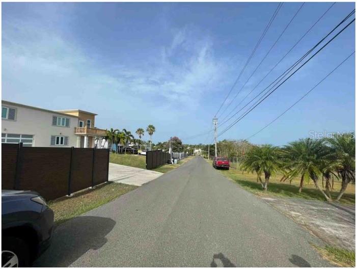 A paved street runs between a residential building with a fence and open grassy lots — SR 308 km 5.8 INT SOLAR MIRADERO LOT # 2, CABO ROJO, PR