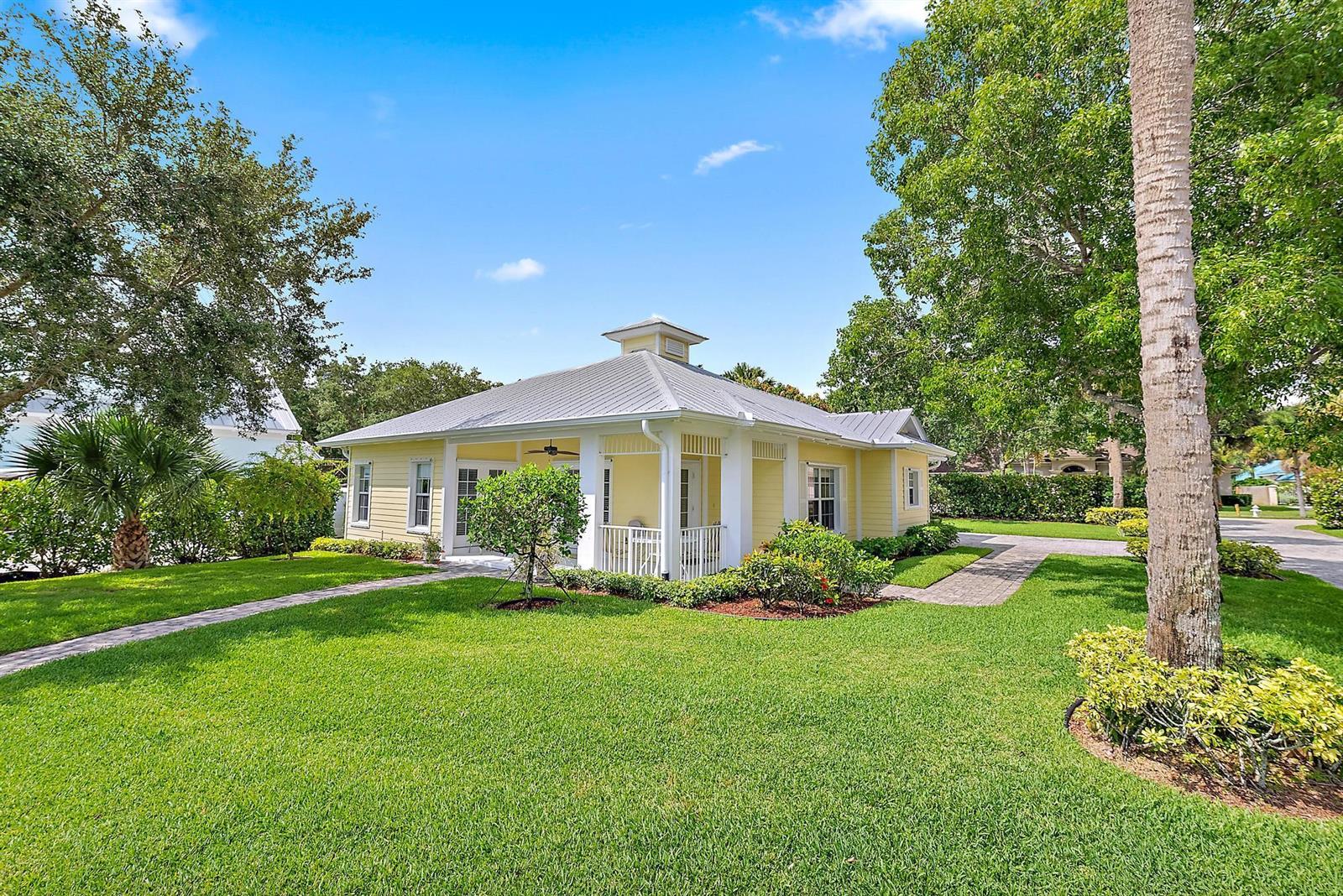 A yellow, single-story house with a metal roof and a covered porch sits on grass — 19043 SE Jupiter River Drive, Jupiter FL 33458, JUPITER, FL