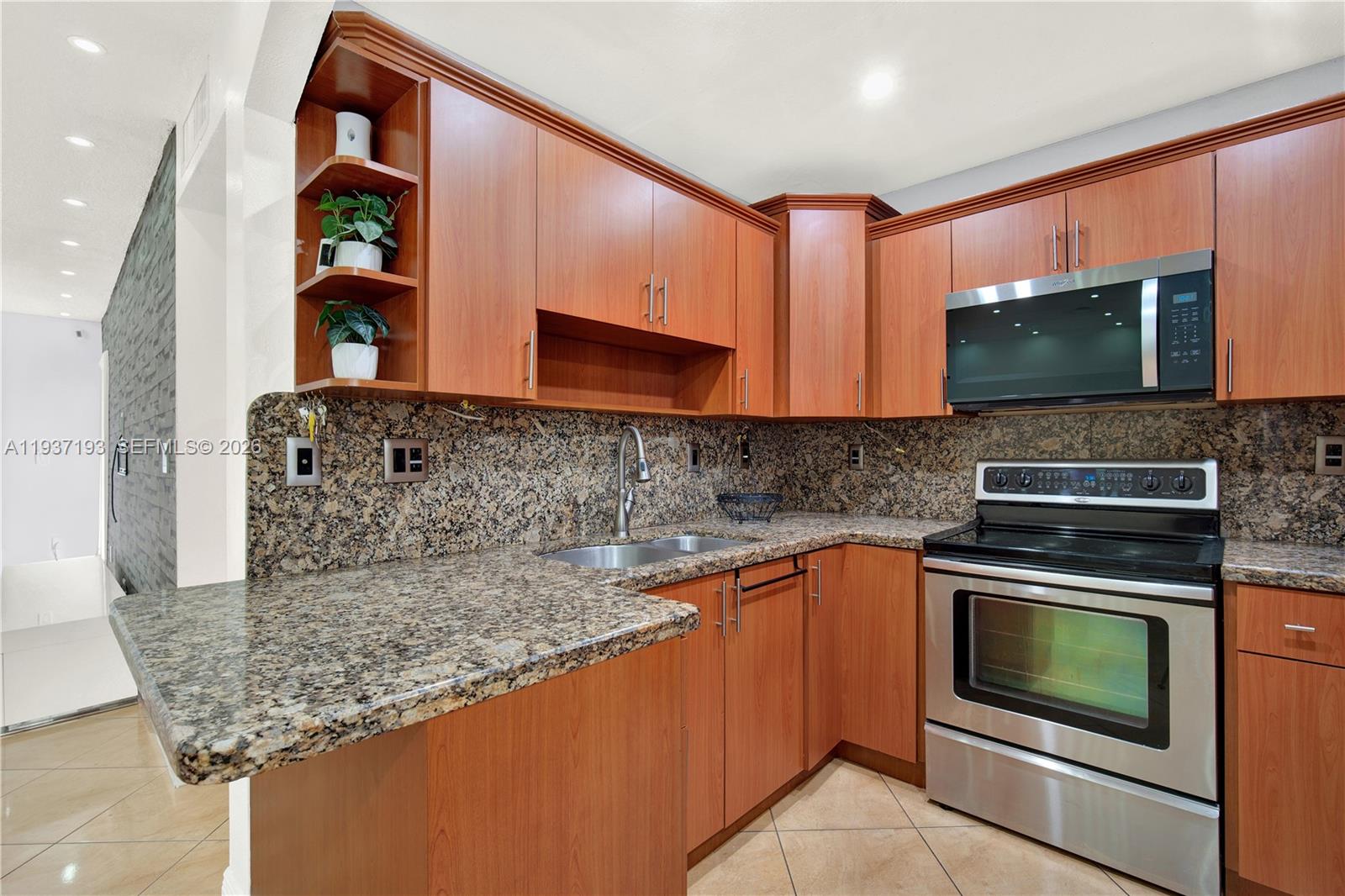 A kitchen features wood cabinets, granite countertops, and stainless steel appliances — 5665 W 20th Ave # 415, Hialeah FL 33012, HIALEAH, FL