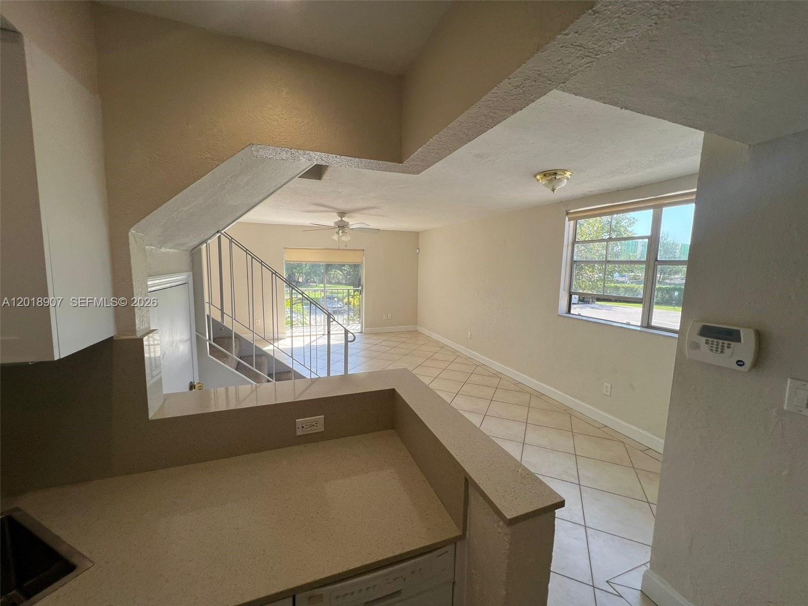 A kitchen counter overlooks a living area with tile floors, a staircase, and a window — 8600 SW 67th Ave # 938, Pinecrest FL 33156, PINECREST, FL
