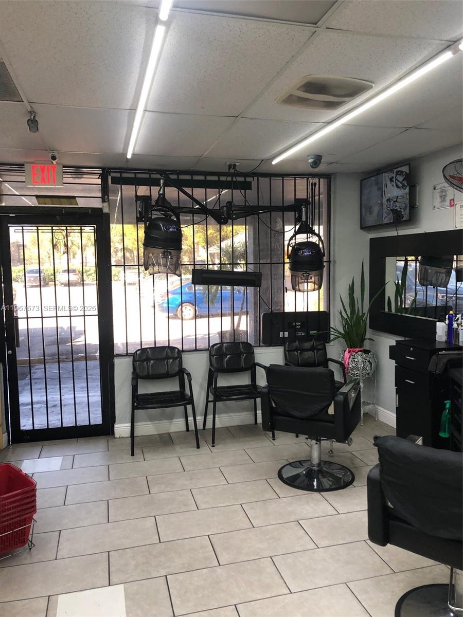 A hair salon interior features two wall-mounted hooded dryers, black styling chairs, and tiled flooring — 57th, Miami Gardens FL 33055, MIAMI GARDENS, FL