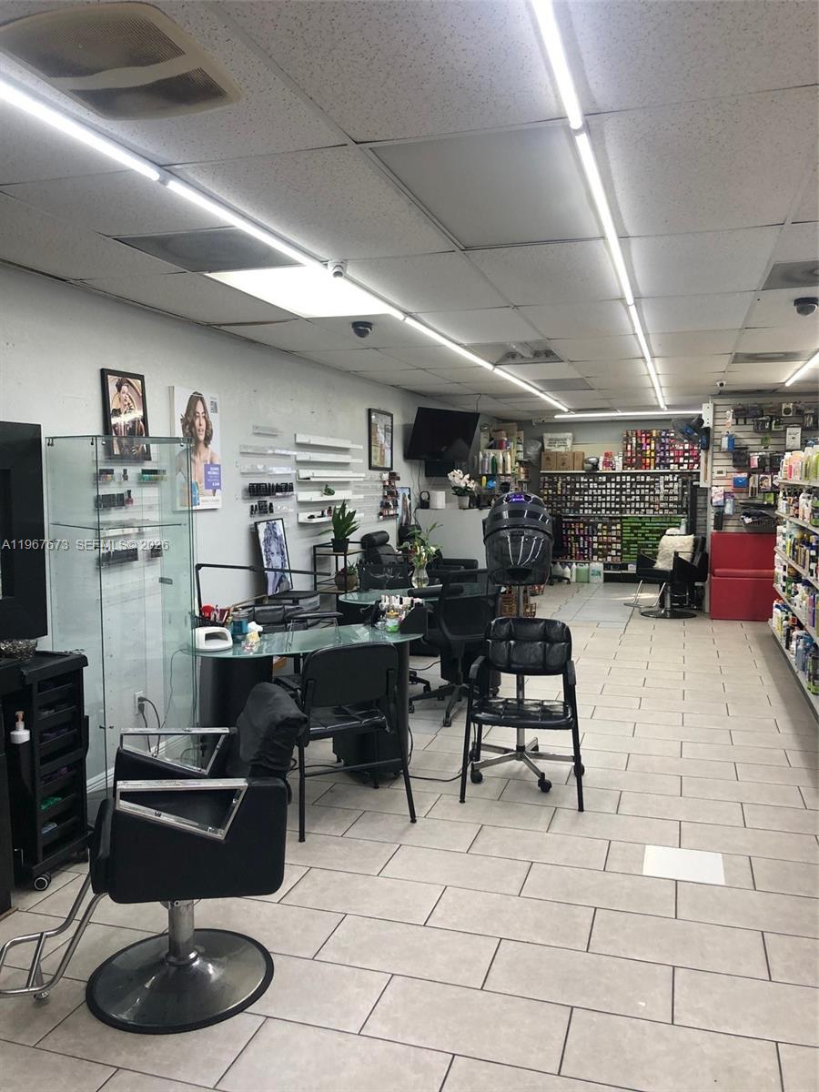A hair and nail salon features multiple styling chairs, workstations, and retail product shelving — 57th, Miami Gardens FL 33055, MIAMI GARDENS, FL