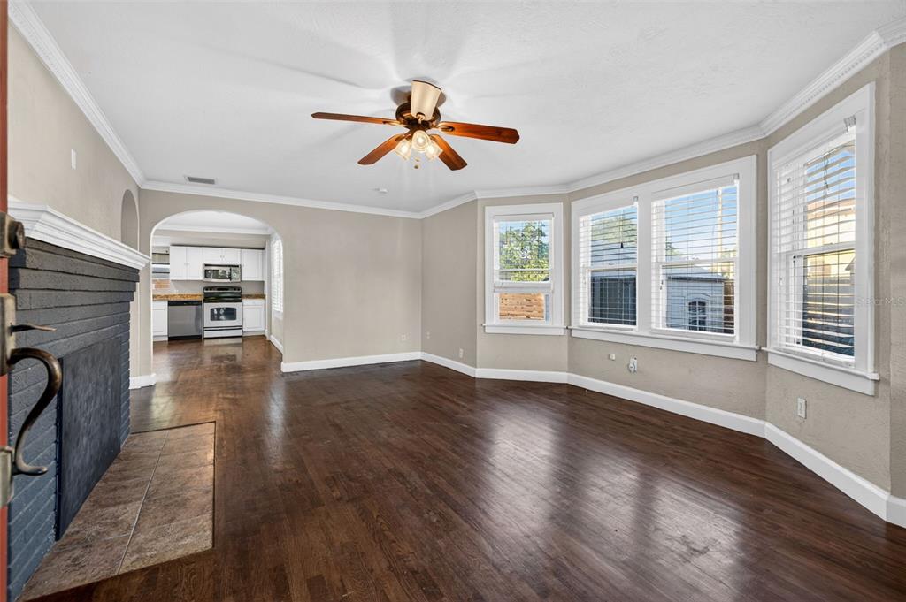 A living room with dark hardwood floors, a brick fireplace, and a bay window — 2419 DARTMOUTH AVENUE N, ST PETERSBURG, FL