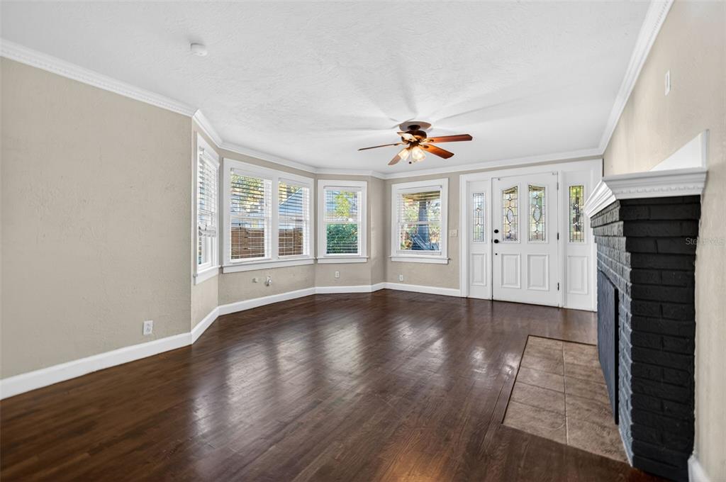 A living room with dark wood floors, a brick fireplace, and a white front door — 2419 DARTMOUTH AVENUE N, ST PETERSBURG, FL