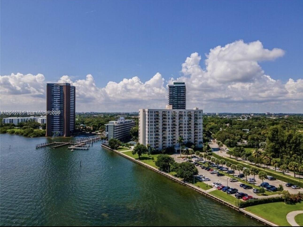 An aerial view shows a waterfront apartment complex with a parking lot and green space — 880 NE 69th St # 11M, Miami FL 33138, MIAMI, FL