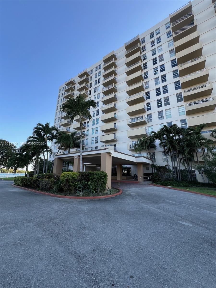 A multi-story residential building features a covered entrance and balconies under a clear blue sky — 880 NE 69th St # 11M, Miami FL 33138, MIAMI, FL