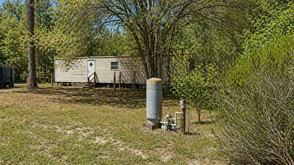 A mobile home sits in a grassy yard with a well pressure tank in front — 11281 NE 64TH PLACE, WILLISTON, FL