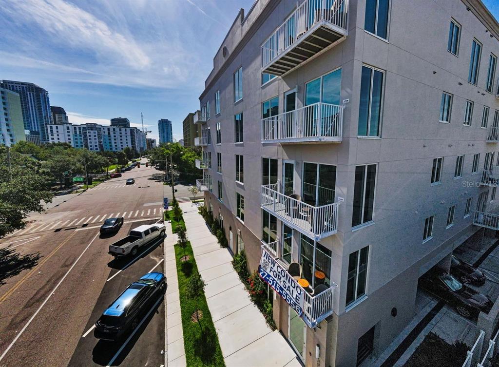 An exterior view of a multi-story apartment building with balconies and a street-level parking area — 600 3RD AVENUE S UNIT 301, ST PETERSBURG, FL