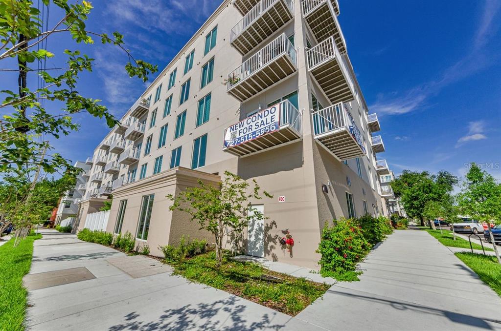 A low-angle exterior view of a multi-story apartment building with balconies and a sidewalk — 600 3RD AVENUE S UNIT 301, ST PETERSBURG, FL
