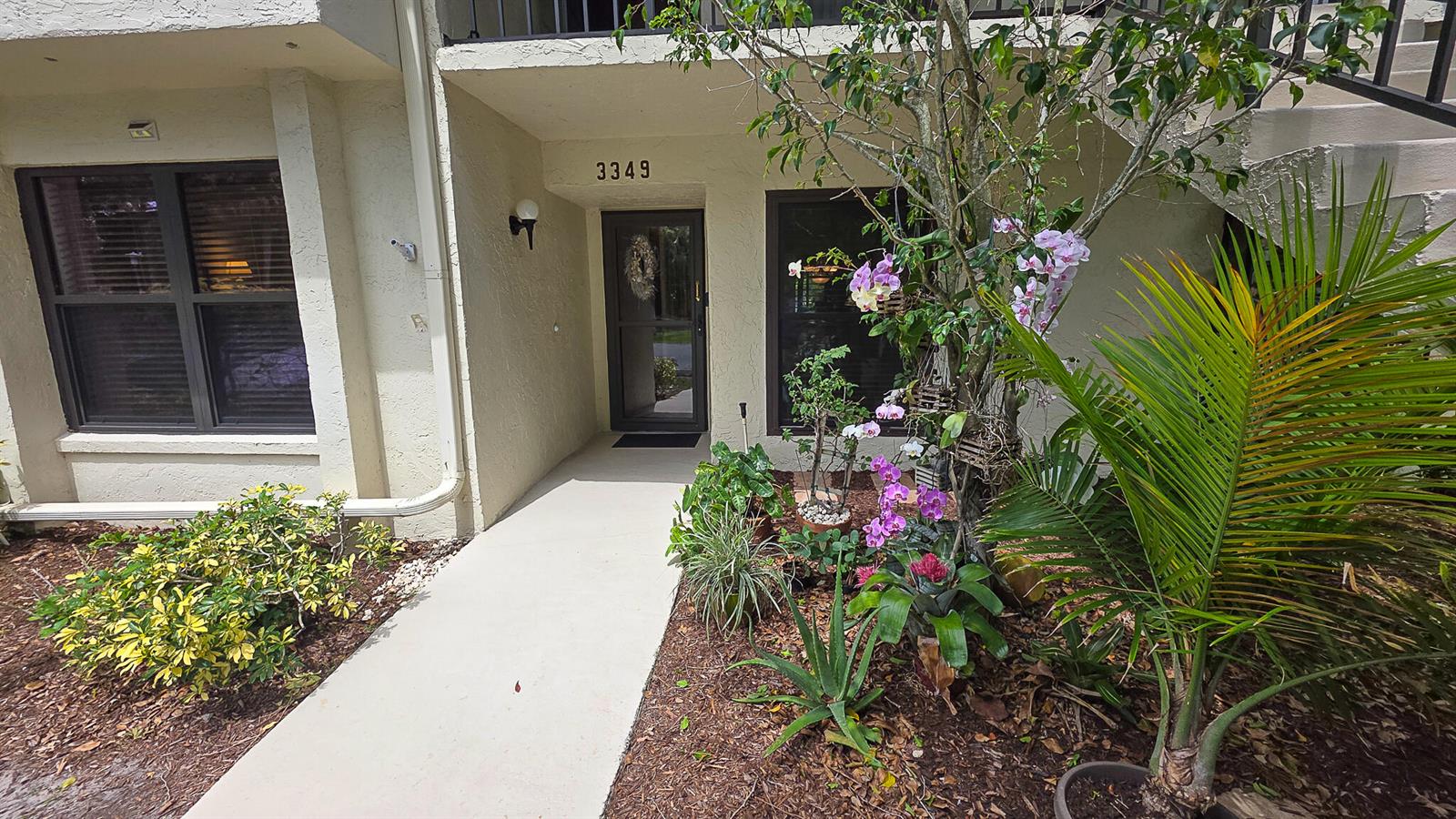 The exterior of a residential unit features a concrete walkway leading to a glass door — 3349 Perimeter Drive, FL 33467, FL