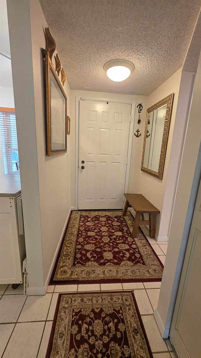 A tiled entryway features a white front door, a wooden bench, and two red rugs — 3349 Perimeter Drive, FL 33467, FL