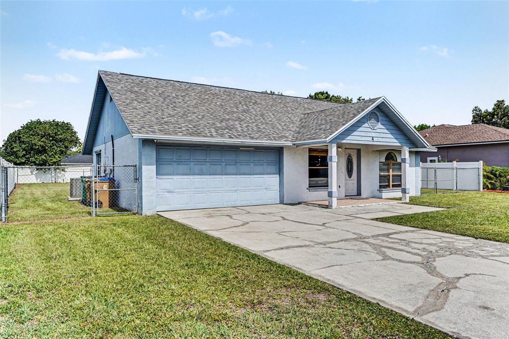 A single-story house with a blue garage, white stucco walls, and a concrete driveway — 4 CARMONA WAY, KISSIMMEE, FL