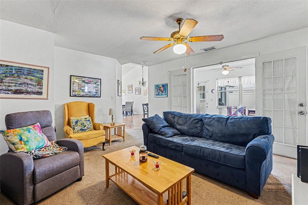 A living room features a blue sofa, a gray armchair, a yellow chair, and carpet — 4 CARMONA WAY, KISSIMMEE, FL