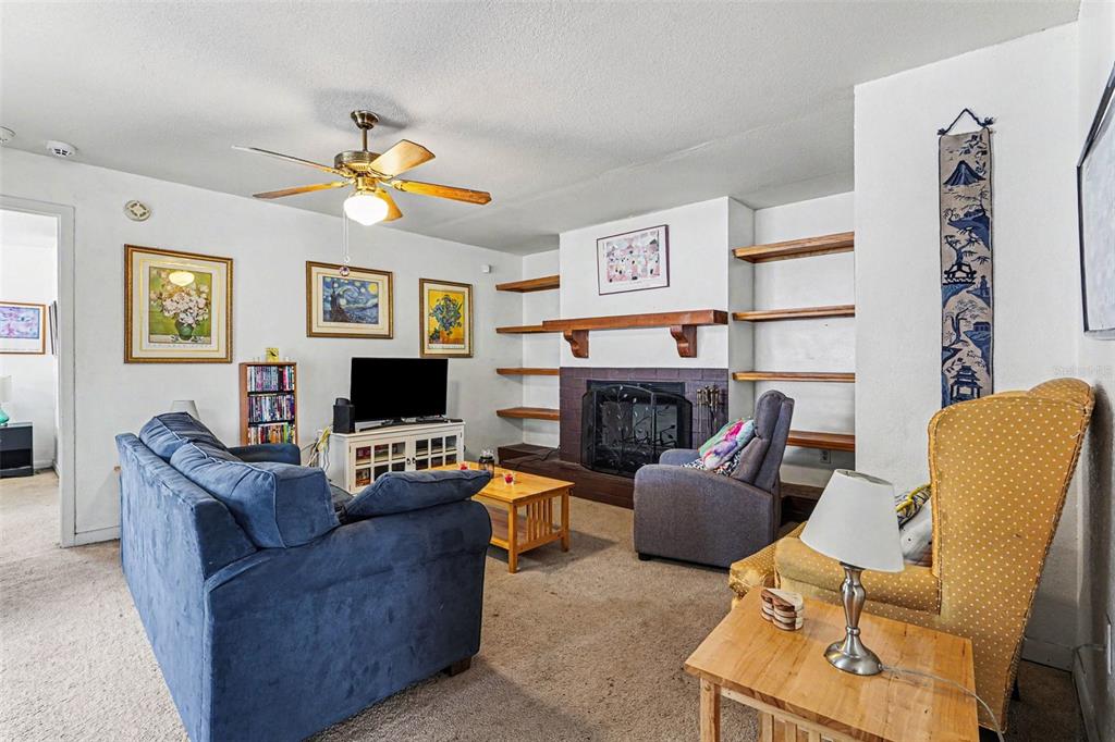 A living room features a fireplace, built-in shelves, a blue sofa, and a yellow armchair — 4 CARMONA WAY, KISSIMMEE, FL