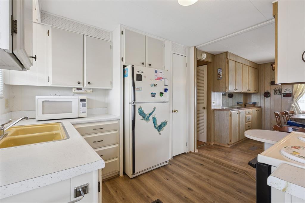A kitchen with white cabinets, a yellow sink, a refrigerator, and wood-look flooring — 13 COCOS PLUMOSA DRIVE UNIT B, EUSTIS, FL