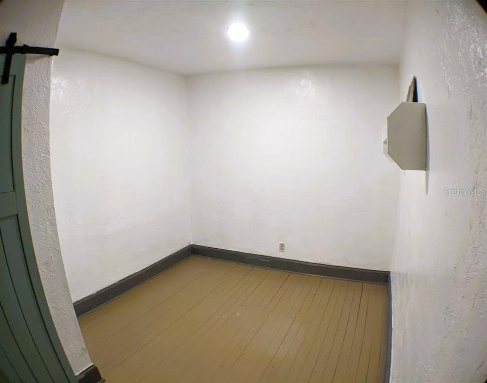 A small, empty room with white walls, a brown wood floor, and a wall-mounted cabinet — 401 COLONIA LANE E UNIT 10, NOKOMIS, FL