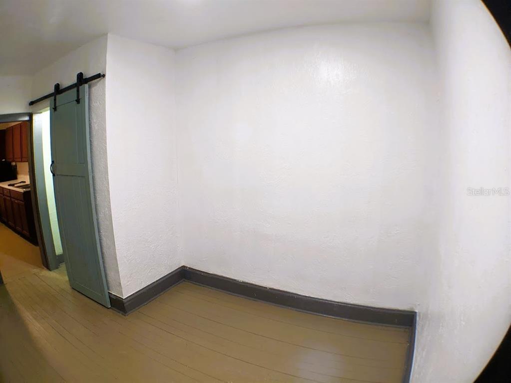 An empty room features white walls, a wooden floor, and a blue sliding barn door — 401 COLONIA LANE E UNIT 10, NOKOMIS, FL