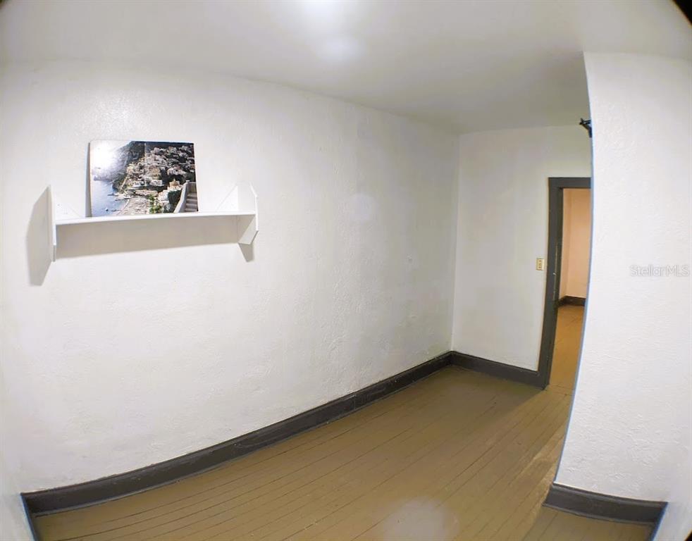 An empty room with white walls, dark wood trim, and a single wall-mounted shelf — 401 COLONIA LANE E UNIT 10, NOKOMIS, FL