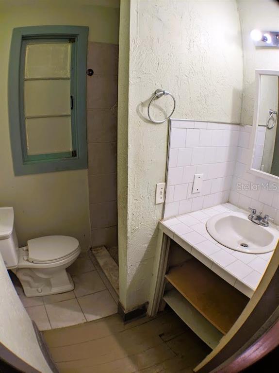 A bathroom with a toilet, a tiled vanity with a sink, and a small window — 401 COLONIA LANE E UNIT 10, NOKOMIS, FL