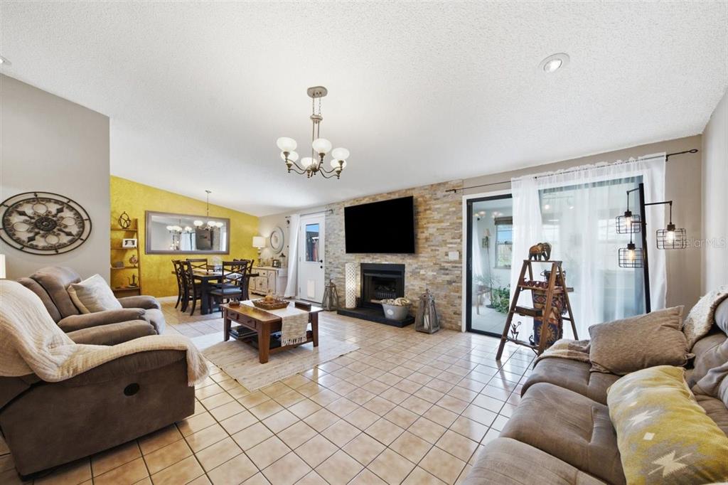 A living room with tile floors, a stone fireplace, and an adjacent dining area — 5309 BLACK PINE DRIVE, TAMPA, FL
