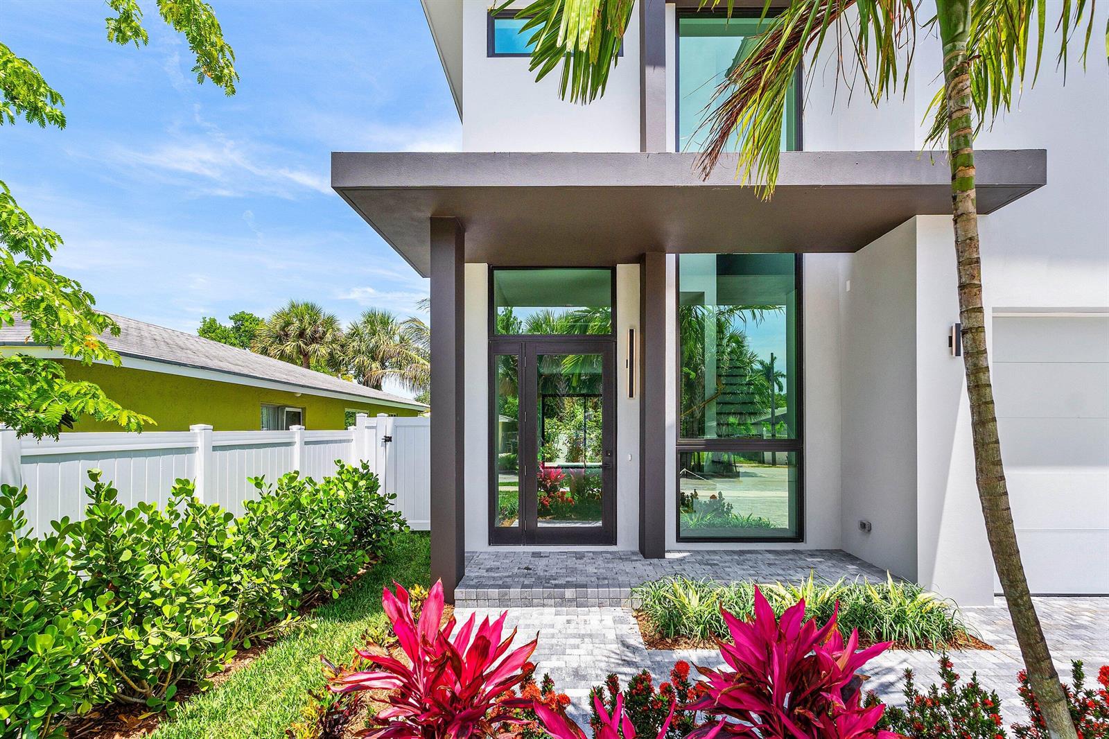 The exterior of a modern house features a glass front door, large windows, and landscaping — 207 SE 5th Street, Delray Beach FL 33483, DELRAY BEACH, FL