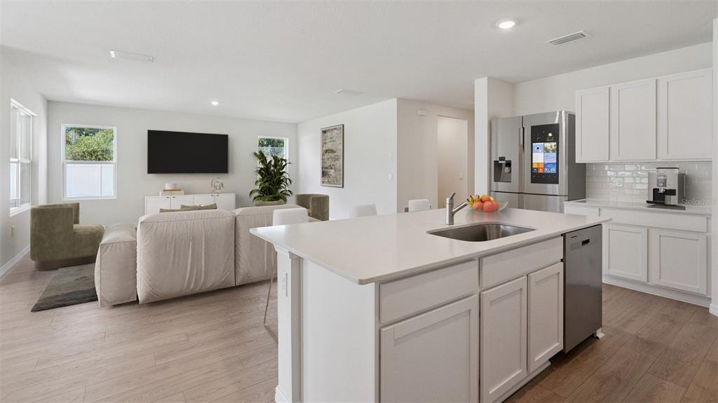 An open-concept kitchen and living area features white cabinetry, a central island, and light flooring — 1124 MORFONTAINE STREET, DAYTONA BEACH, FL