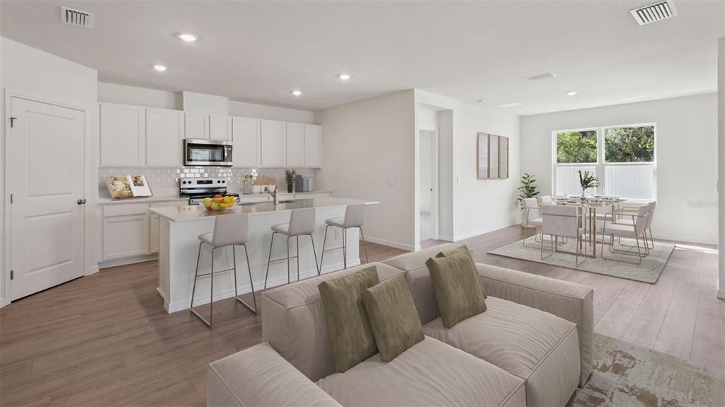 An open-concept kitchen with white cabinets and an island overlooks a living and dining area — 1124 MORFONTAINE STREET, DAYTONA BEACH, FL
