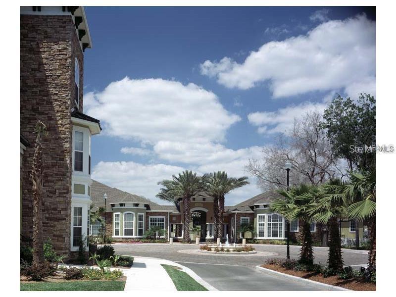 A stone-faced building exterior features a circular driveway with a central fountain and palm trees — 10025 COURTNEY PALMS  BOULEVARD UNIT 103, TAMPA, FL