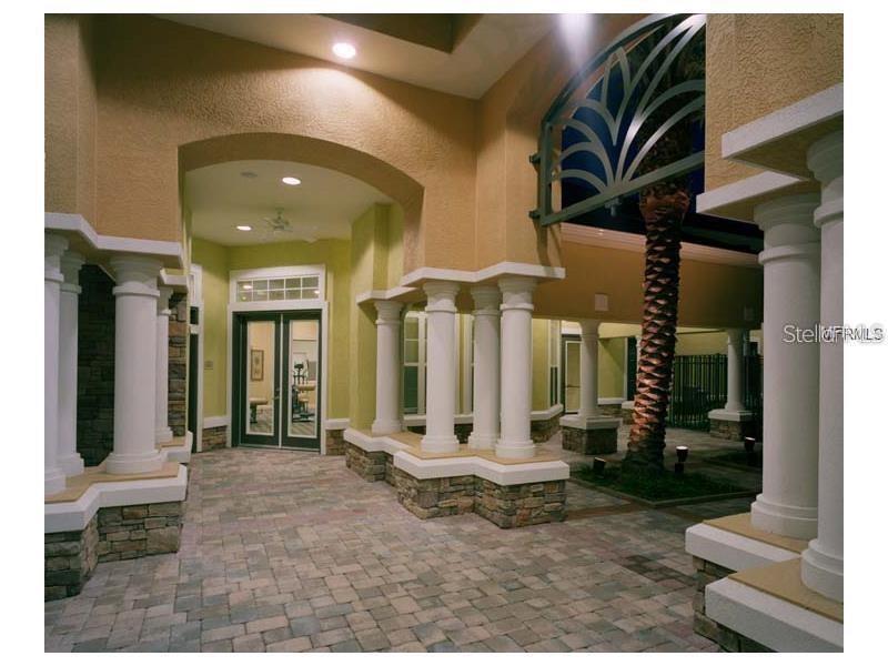 A covered outdoor patio features stone-based columns, paver flooring, and a palm tree — 10025 COURTNEY PALMS  BOULEVARD UNIT 103, TAMPA, FL
