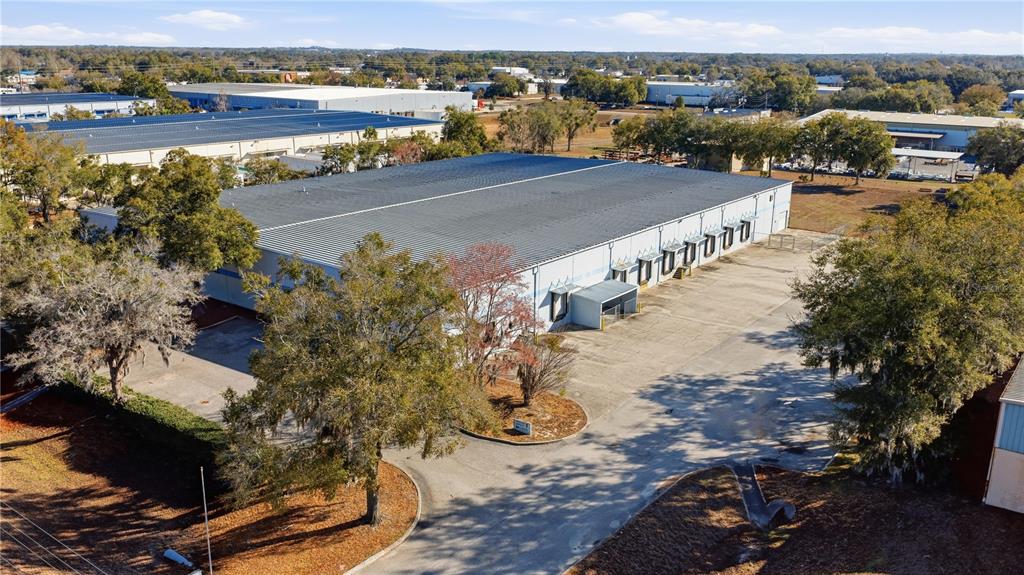 An aerial view shows a large industrial warehouse building with multiple loading docks and parking — 451 SW 57TH AVENUE, OCALA, FL