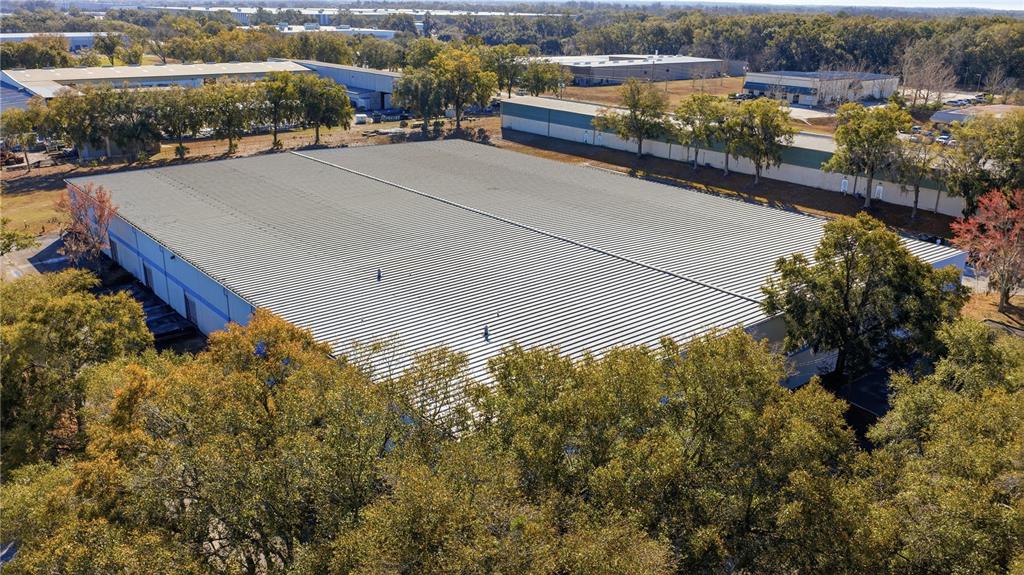 An aerial view shows a large industrial warehouse building surrounded by trees and parking areas — 451 SW 57TH AVENUE, OCALA, FL