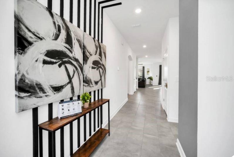 A hallway features a console table against a wall with black vertical stripes and artwork — 9149 SOMMERSET HILLS DRIVE, DAVENPORT, FL