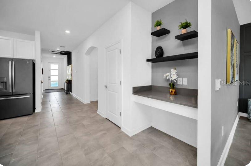 A kitchen area features a dark refrigerator, gray tile flooring, and a built-in desk nook — 9149 SOMMERSET HILLS DRIVE, DAVENPORT, FL