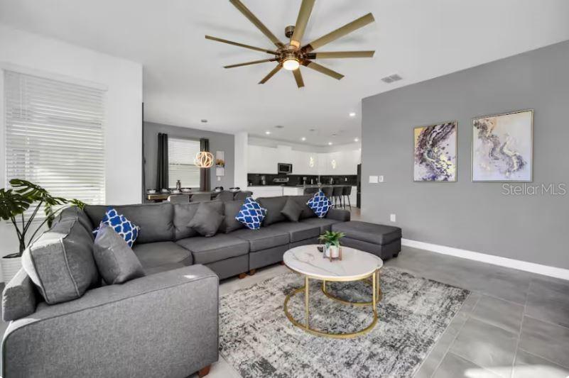 A living room features a large gray sectional sofa, a round coffee table, and ceiling fan — 9149 SOMMERSET HILLS DRIVE, DAVENPORT, FL
