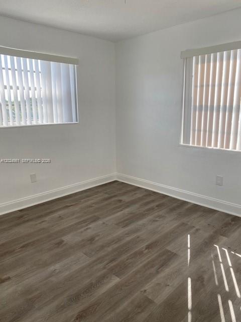 An empty room features white walls, light wood-look flooring, and two windows with vertical blinds — 5960 NE 5th Ct # 4, Miami FL 33137, MIAMI, FL