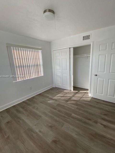 A bedroom with light gray wood-look flooring, a window with vertical blinds, and a closet — 5960 NE 5th Ct # 4, Miami FL 33137, MIAMI, FL