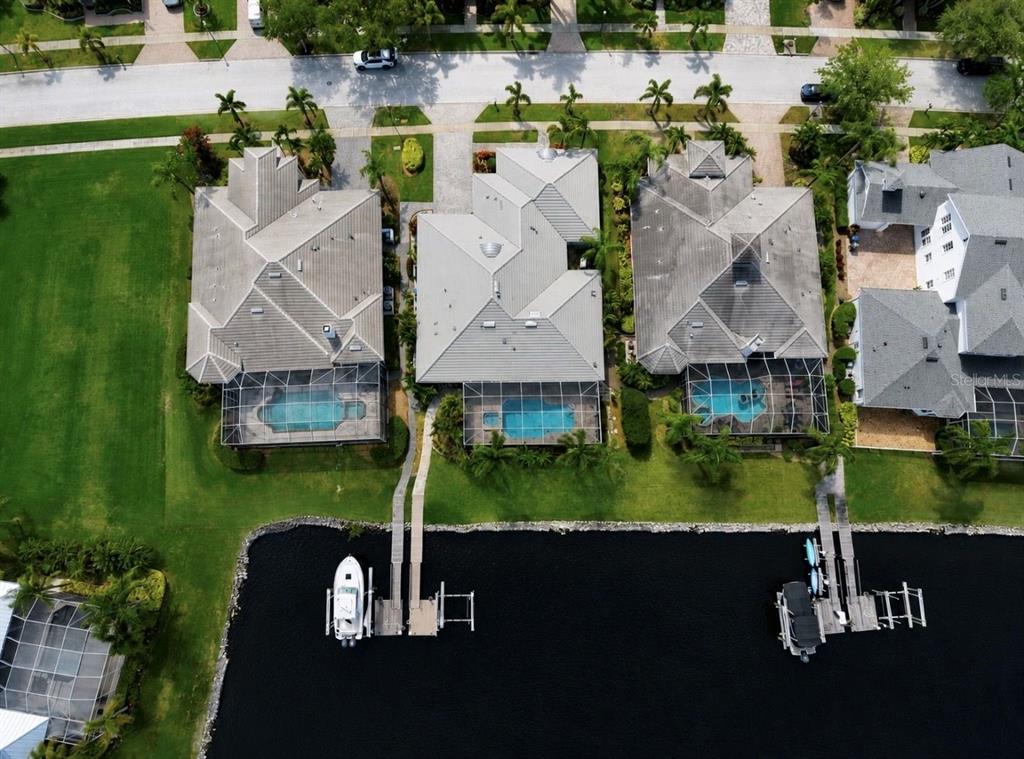 An aerial view shows three waterfront houses with pools, screened lanais, and private boat docks — 5416 MERRITT ISLAND DRIVE, APOLLO BEACH, FL