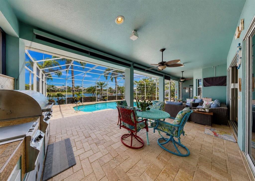 A covered patio features a grill, dining set, lounge furniture, and a screened-in swimming pool — 5416 MERRITT ISLAND DRIVE, APOLLO BEACH, FL