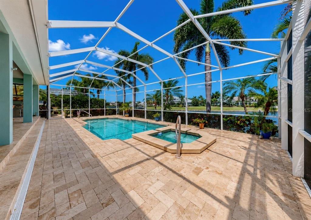 A screened-in pool and spa area with stone pavers and views of a lake — 5416 MERRITT ISLAND DRIVE, APOLLO BEACH, FL