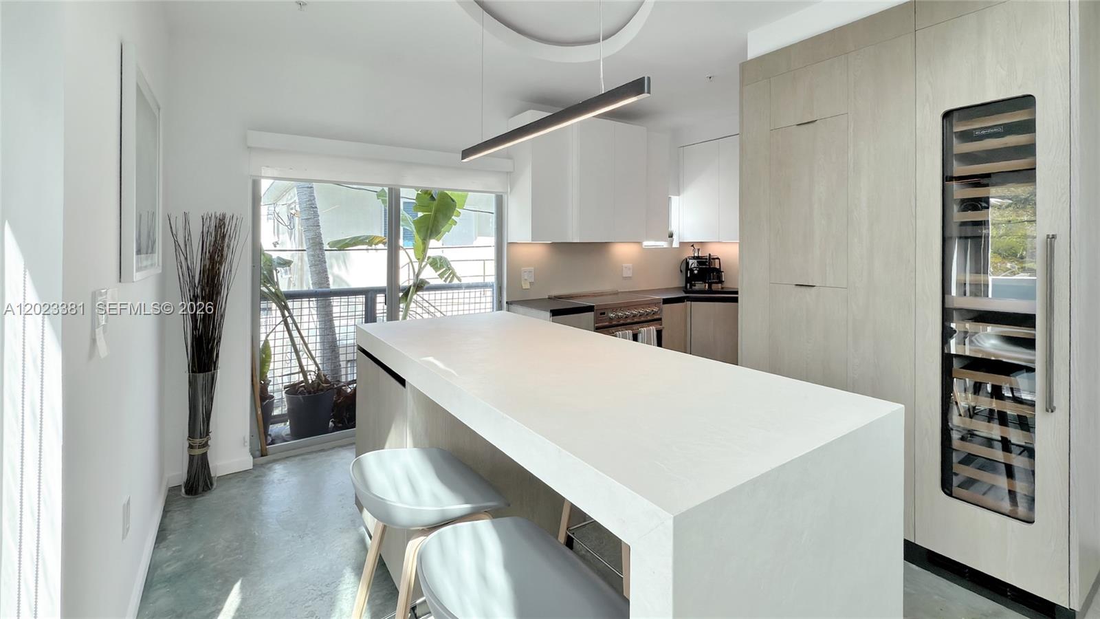 An outdoor balcony features a metal railing, potted plants, seating, and a gray door — 734 Michigan Ave # 7, Miami Beach FL 33139, MIAMI BEACH, FL
