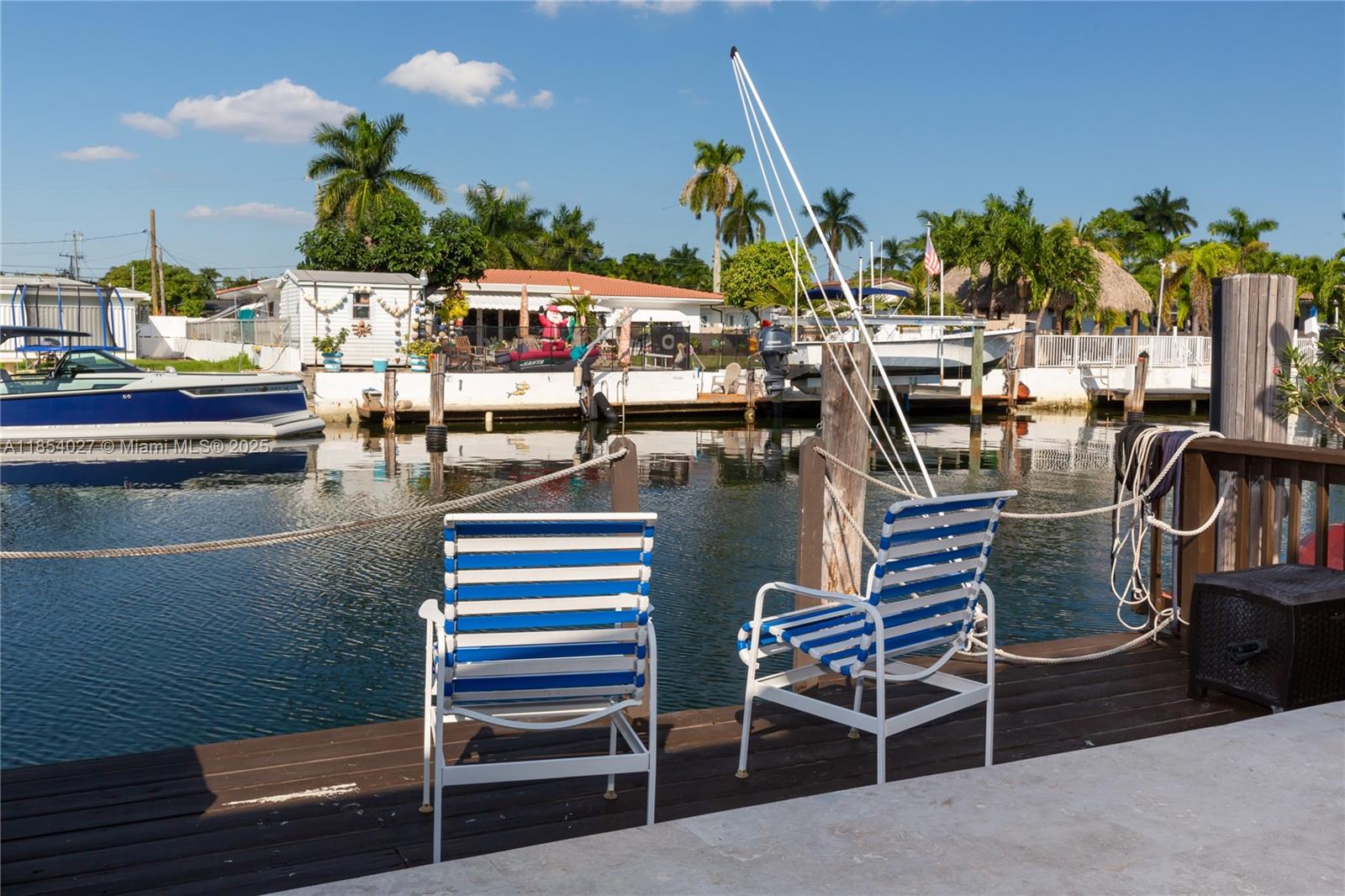 Two blue and white striped chairs sit on a wooden dock overlooking a canal — 2035 NE 123rd St, North Miami FL 33181, NORTH MIAMI, FL