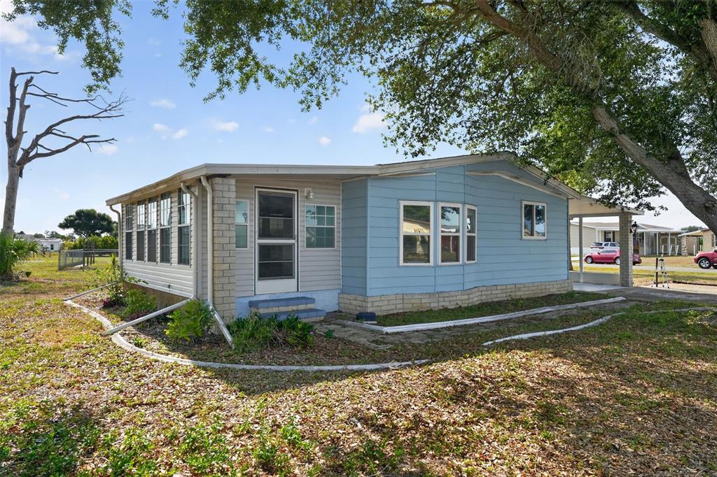 A single-story manufactured home with blue and beige siding sits on a grassy lot — 6198 ORIOLE BOULEVARD, ENGLEWOOD, FL