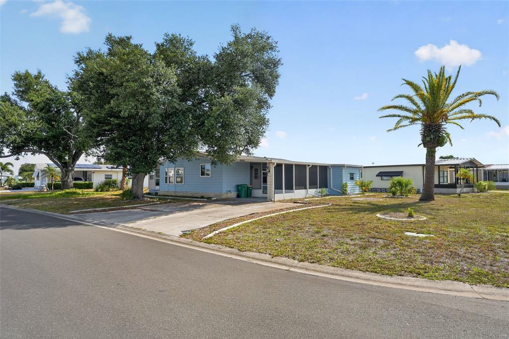 A light blue single-story mobile home features a concrete driveway and a screened-in porch — 6198 ORIOLE BOULEVARD, ENGLEWOOD, FL