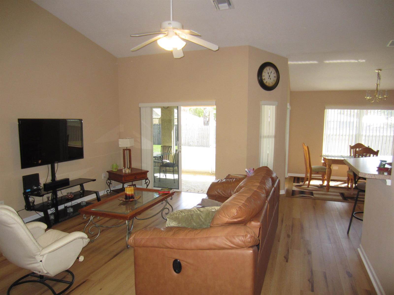 A living room with a leather sofa, white recliner, glass coffee table, and sliding glass doors — 4702 Seagrape Drive, Fort Pierce FL 34982, FORT PIERCE, FL