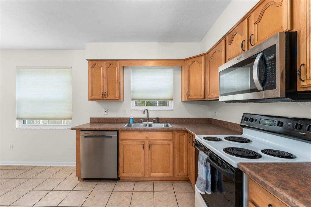 A kitchen features wood cabinets, stainless steel appliances, and tile flooring — 2026 SW 73RD STREET, GAINESVILLE, FL