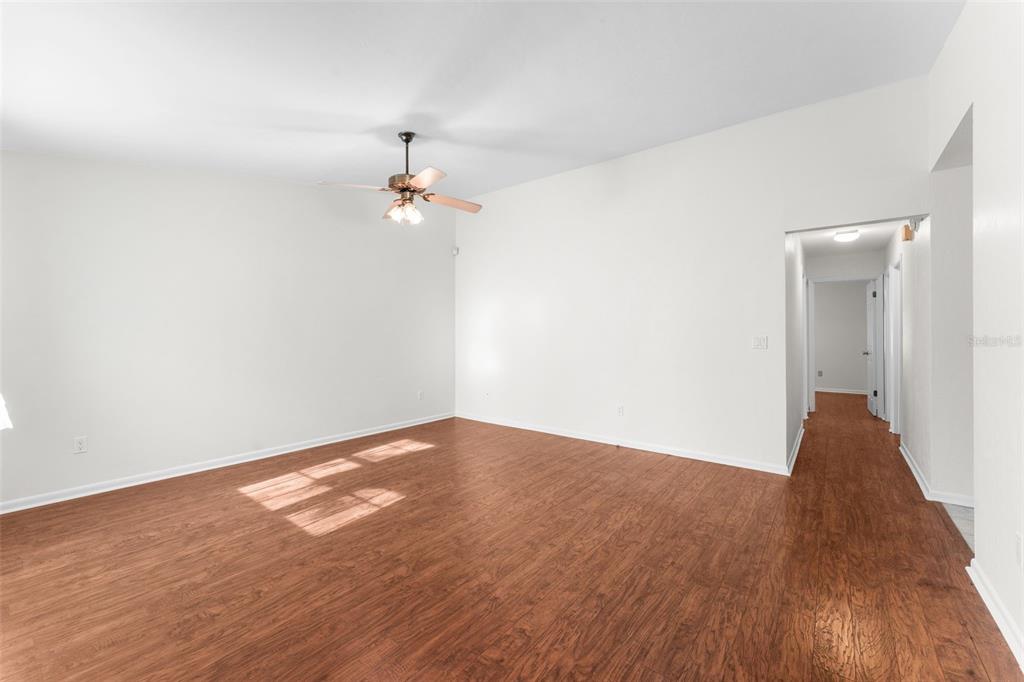 An empty room with wood-look flooring, a ceiling fan, and a doorway leading to a hallway — 2026 SW 73RD STREET, GAINESVILLE, FL