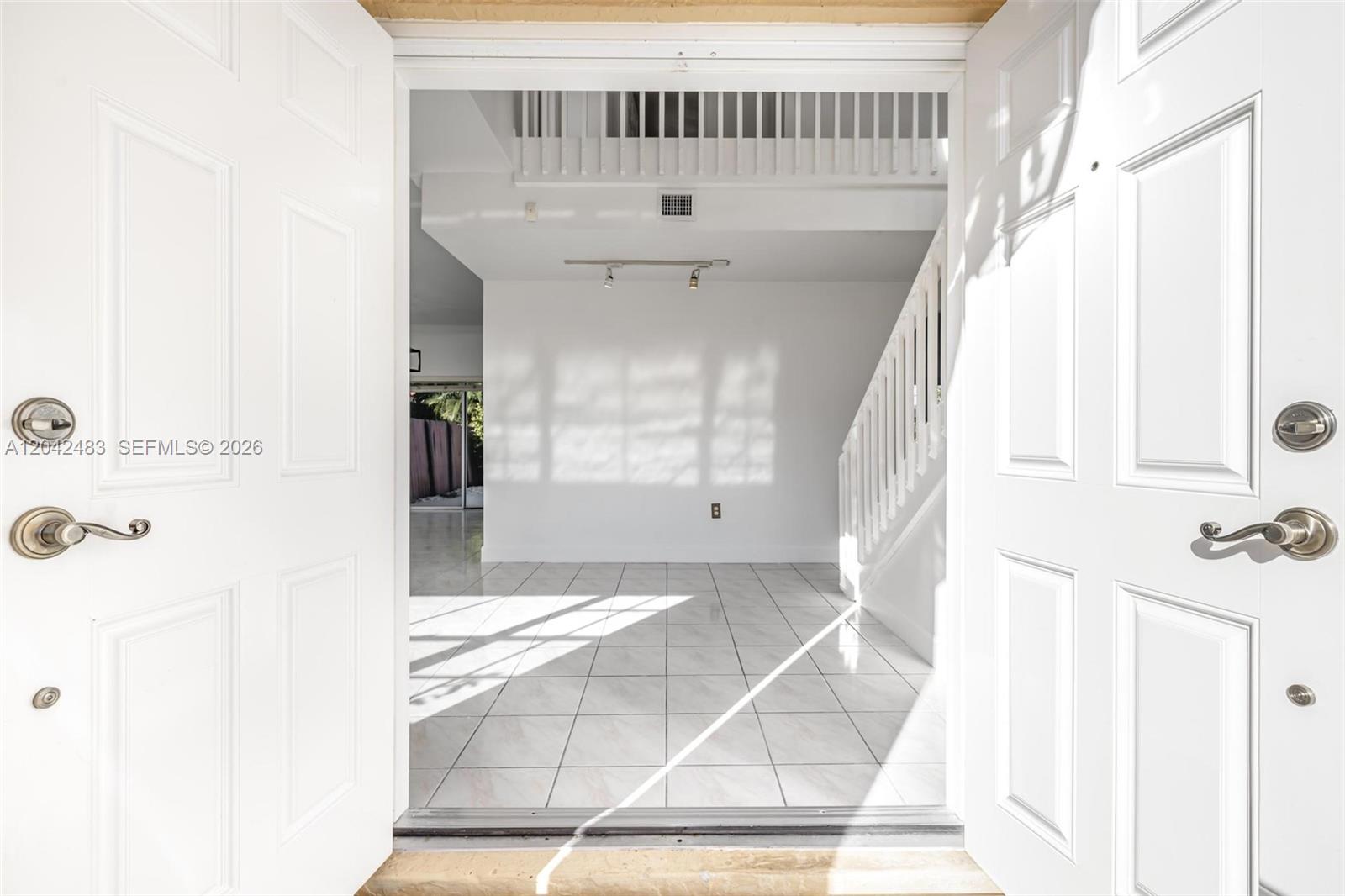 A view through an open double door into a tiled foyer with a staircase — 4671 SW 154th Pl, Miami FL 33185, MIAMI, FL