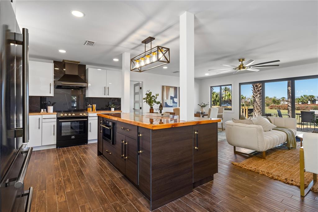 A modern kitchen features a dark wood island, white cabinetry, and an open-concept living area — 203 PARKWOOD LANE, EDGEWATER, FL