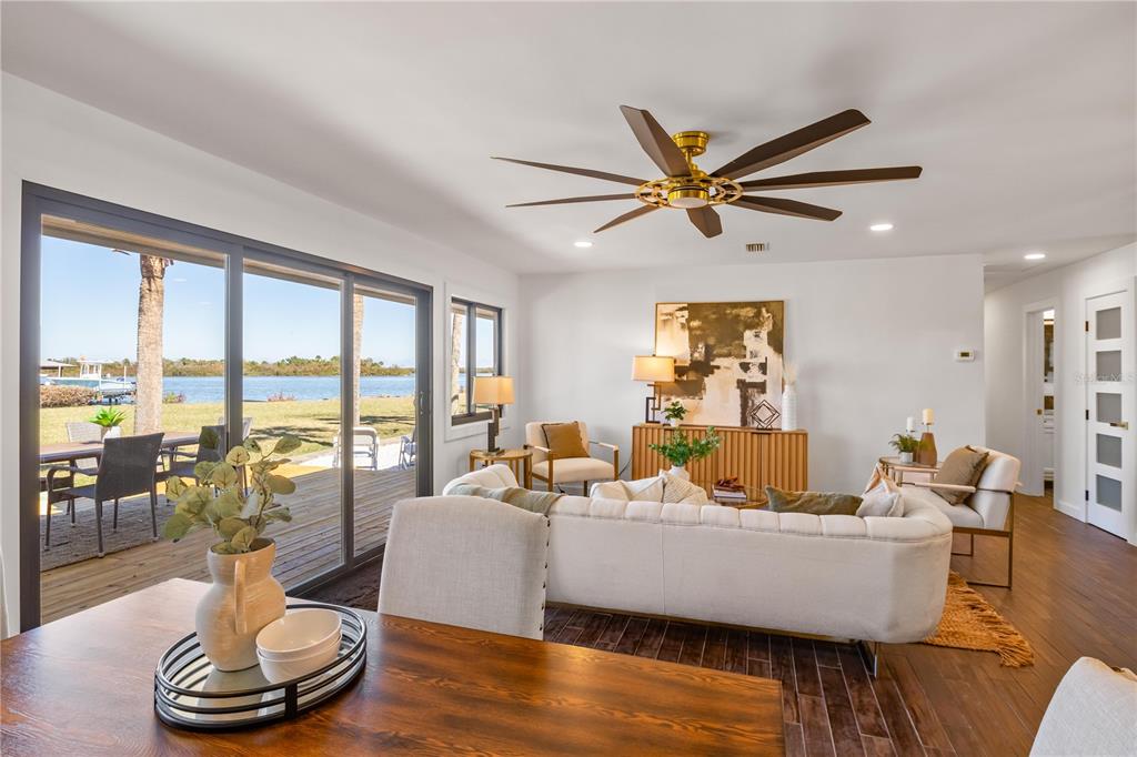 A living room with a large sliding glass door overlooking a waterfront deck and yard — 203 PARKWOOD LANE, EDGEWATER, FL