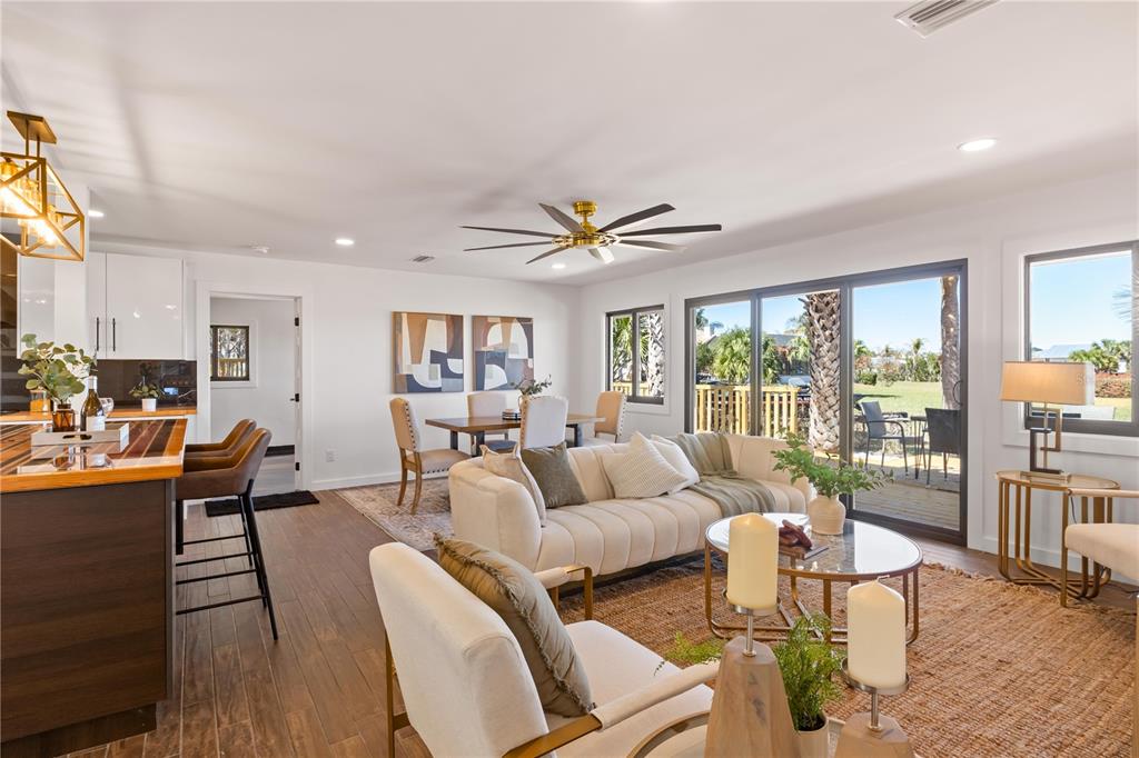 An open-concept living and dining area features white walls, wood-look tile floors, and sliding doors — 203 PARKWOOD LANE, EDGEWATER, FL